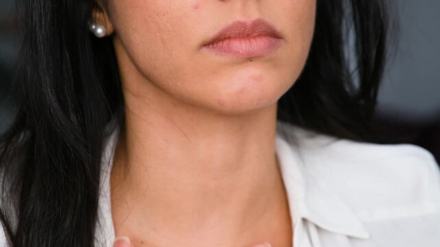 Close up of a woman with sore throat. She is touching her neck
