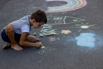 Fototapeta premium the boy draws with chalk on the asphalt. Selective focus