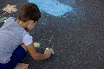 Naklejka premium the boy draws with chalk on the asphalt. Selective focus