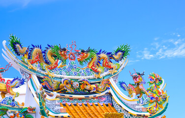 Colorful traditional dragon with Qilin Kirin and swan statues on top of Chinese shrine roof against...