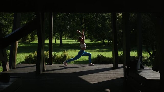 Girl doing yoga flow dance at sunrise in a city park.