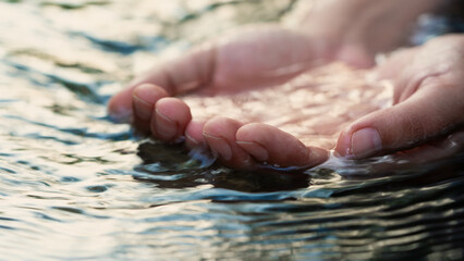 A female hand touching the river water	
