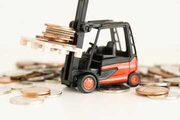 Red forklift truck carrying piles of coins, investments or business growth concept