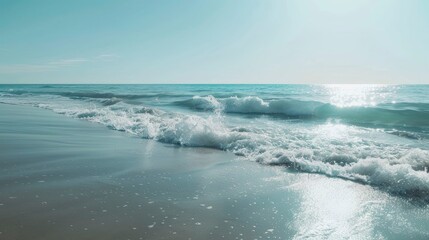 A serene beach with gentle waves and a clear blue sky.