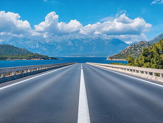Scenic coastal road with mountain backdrop under blue sky on a sunny day