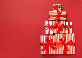 Gift boxes in Christmas tree shape on color background, top view