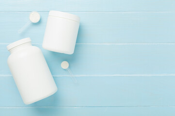 Jar with protein powder on wooden background, top view. Sports nutrition concept