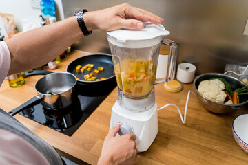 Chef at the kitchen preparing pumpkin porridge with tofu and vegetables