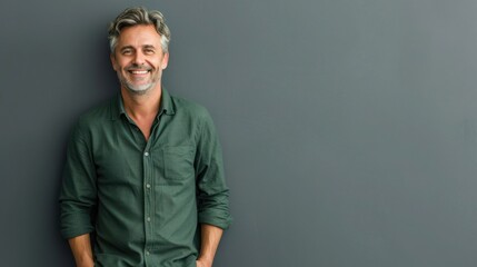 Obraz premium Smiling stylish middle aged business man, happy older mature businessman professional executive wearing green shirt looking at camera standing isolated on gray background. Portrait. Copy space. 