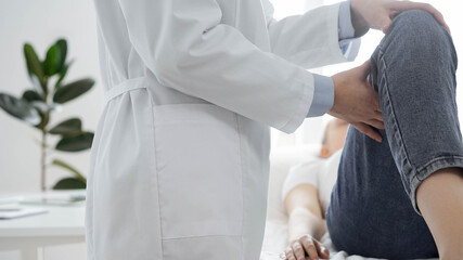 Obraz premium Doctor and patient are at the medical inspection in clinic. Orthopedic examines the knee of a young woman. Medicine concept