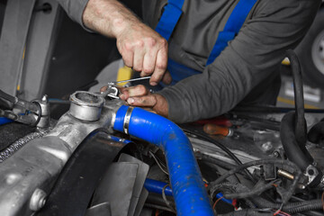 A mechanic meticulously adjusts engine components using a wrench in a well-equipped garage. The focus is on the intricate details of the machinery and the skilled hands at work, illustrating a moment 