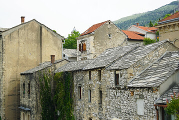 Traditional architecture of Bosnia and Herzegovina in the Old Town of Mostar: view of old houses with roofs made of stone slabs. Buildings between Kujundjiluk and Marshal Tito streets.