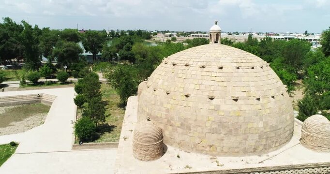 A drone flies close around a Ismoil Somoniy madrasah on a sunny day. Uzbekistan, Bukhara.