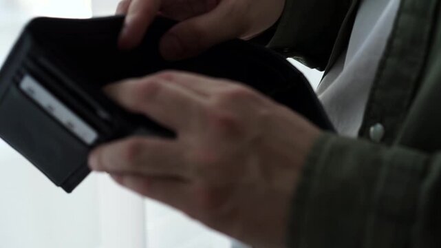 A man is looking for money in his wallet.
Empty wallet.
Lack of money, financial problems