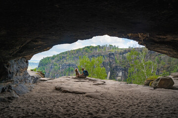 dog and person sitting in the cave in saxon switzerland