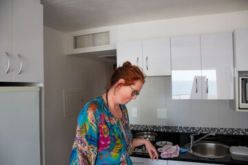 redhead middle age woman with freckles cooking in the kitchen, south african lifestyle, Afrikaans woman