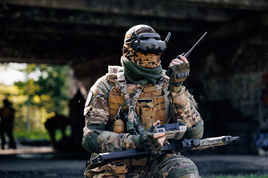 UAV Army operator in FPV glasses controls drone with bomb to drop into enemy fortifications and trenches - Powered by Adobe