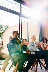Colleagues attending seminar clapping in praise during assembly