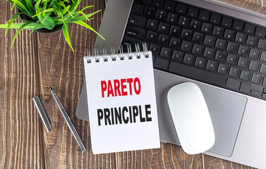 PARETO PRINCIPLE text on notebook with laptop, mouse and pen . .