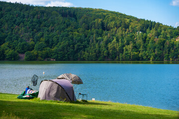 Summer camping by the river with a tent and fishing gear in Czech nature on the grassy beach