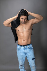 Naklejka premium Cropped view of a young shirtless athlete with black towel after shower, bath or sauna. Indian bodybuilder with happy, mischievous facial expressions posing for camera