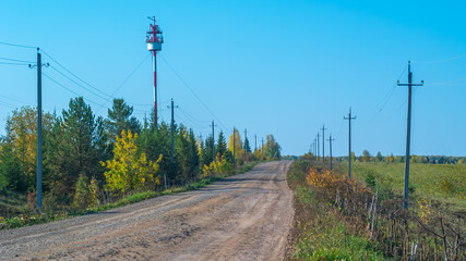 In the distance, you can see a tower with antennas for cellular and Internet communications. Poles with electrical wires are installed along the road. Transmission of electricity outside the city.