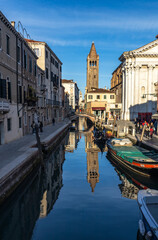 Bateaux et petit pont sur un canal à Venise avec un clocher en arrière-plan