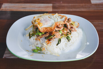 Pork with basil and fried egg on rice is ready to eat on the table.