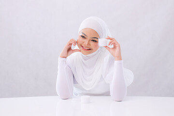 closeup Beautiful young girl asia headscarf happy left to camera hand sign love hand pinching cosmetic cream for skin care product introduction on white background. advertising, health, medical