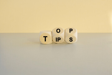 Top tips symbol. Turned wooden cubes with words 'Top tips'. Beautiful grey table, beige background. Top tips and business concept.