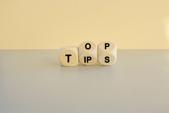 Top tips symbol. Turned wooden cubes with words 'Top tips'. Beautiful grey table, beige background. Top tips and business concept.