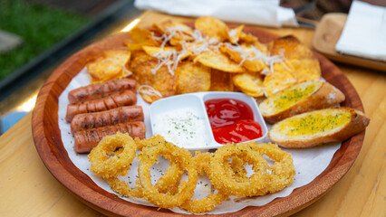 photo of fried potatoes and fried onions rings, in a photo at a restaurant, served with chilli sauce