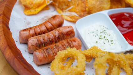 photo of fried potatoes and fried onions rings, in a photo at a restaurant, served with chilli sauce