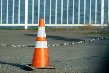 An old traffic cone sign with metal chain 