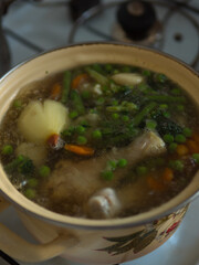 Chicken Soup in a Yellow Pot on the Stove. Vertical close up.