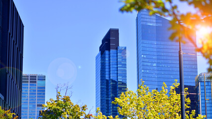 City life, urban landscape and ecology.  Modern office complex with glass facades and smooth lines against backdrop of green trees, concept of modern architecture. Organically building into nature.
