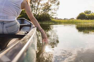 Woman enjoying an amazing summer nature scene while canoeing in the lake, rear view. Canoe adventure and relaxing concepts.