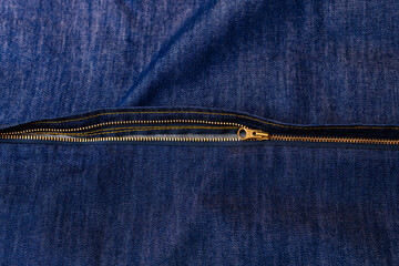 Close-up of a zipper on a denim fabric, showing the detailed stitching and metal teeth of the zipper. © Alena Vilgelm