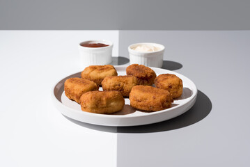 Plato de croquetas fritas con salsa de tomate y mayonesa aperitivo sobre fondo gris