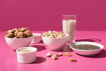 Semillas de chía, sésamo, nueces y pistachos. Frutos secos sobre un fondo rosa