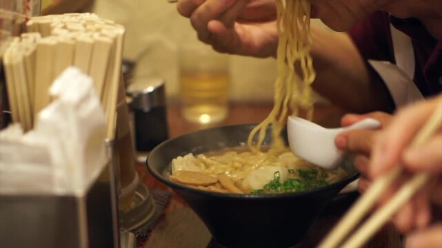 Senior elderly eating hot ramen noodle with chopsticks in Japanese restaurant