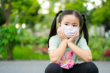 Wearing respirator mask concept. Asian little child girl wearing respirator mask to protect coronavirus outbreak and against PM 2.5 air pollution in Bangkok city. Thailand.