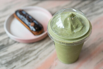 Matcha green tea smoothie and chocolate eclair on marble table