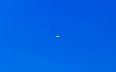 Passenger airplane flies in blue sky with clouds in Mexico.