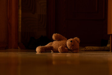 Brown soft teddy bear lies on the floor in the hallway in the apartment abandoned by itself