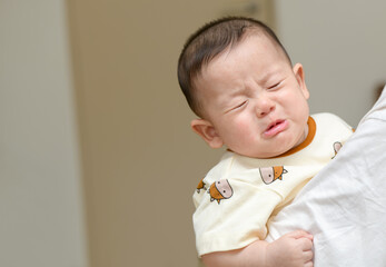 Asian infant crying baby. child tired and hungry 
in mother arms. Children cry. Asia baby...