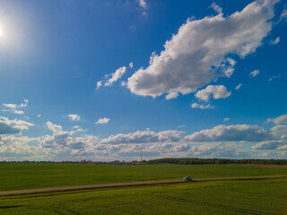 Fototapeta premium Landscape view from drone, green fields and forest, sky with white clouds. 