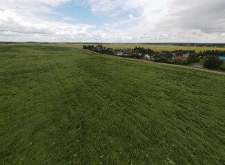 Landscape view from drone, yellow and green fields and haystacks, sky with white clouds. 