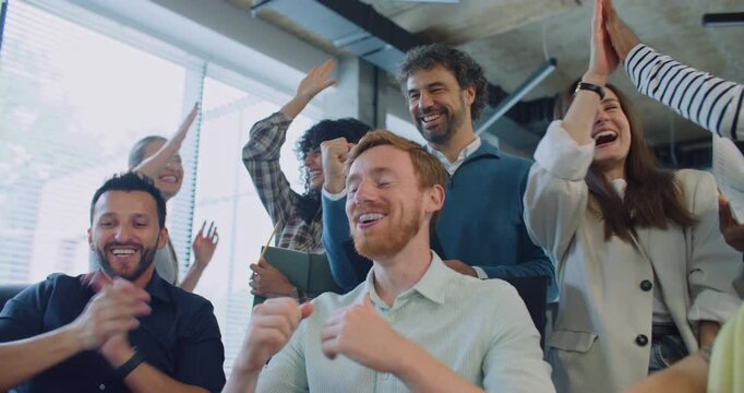 Team building moment. Multi-ethnic group of people exclaiming loudly after looking at monitor. Finding mistake together. Correct solution. Programmers happy about positive result of major problem.