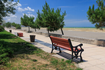 Wooden benches and sun loungers for relaxing on the embankment near the sea, public places